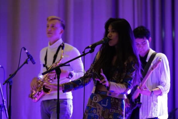 Saxophonist, singer and guitarist on stage in purple light